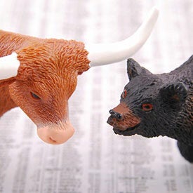 A bull and a bear figurine facing each other, symbolizing the bullish and bearish trends in the stock market.