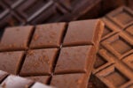 Close-up of several chocolate bars dusted with cocoa powder, showcasing their rich texture and pattern of square segments.