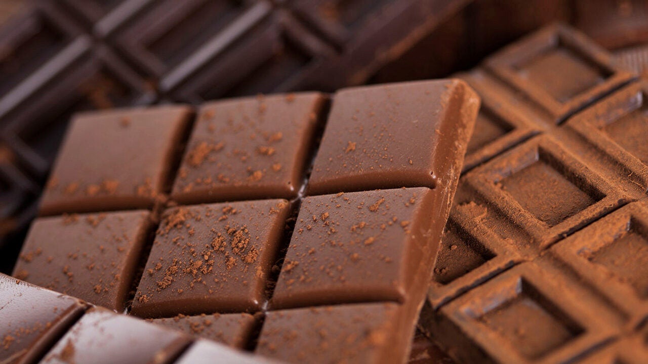 Close-up of several chocolate bars dusted with cocoa powder, showcasing their rich texture and pattern of square segments.