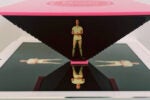A hologram pyramid setup on a tablet, creating a 3D holographic image of a person standing with crossed hands.