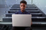 A person sits on stairs using a laptop, with a digital network overlay, representing connectivity and technology.