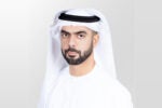 A headshot of a person wearing traditional Middle Eastern attire, including a white keffiyeh and white clothing, on a light gray background.