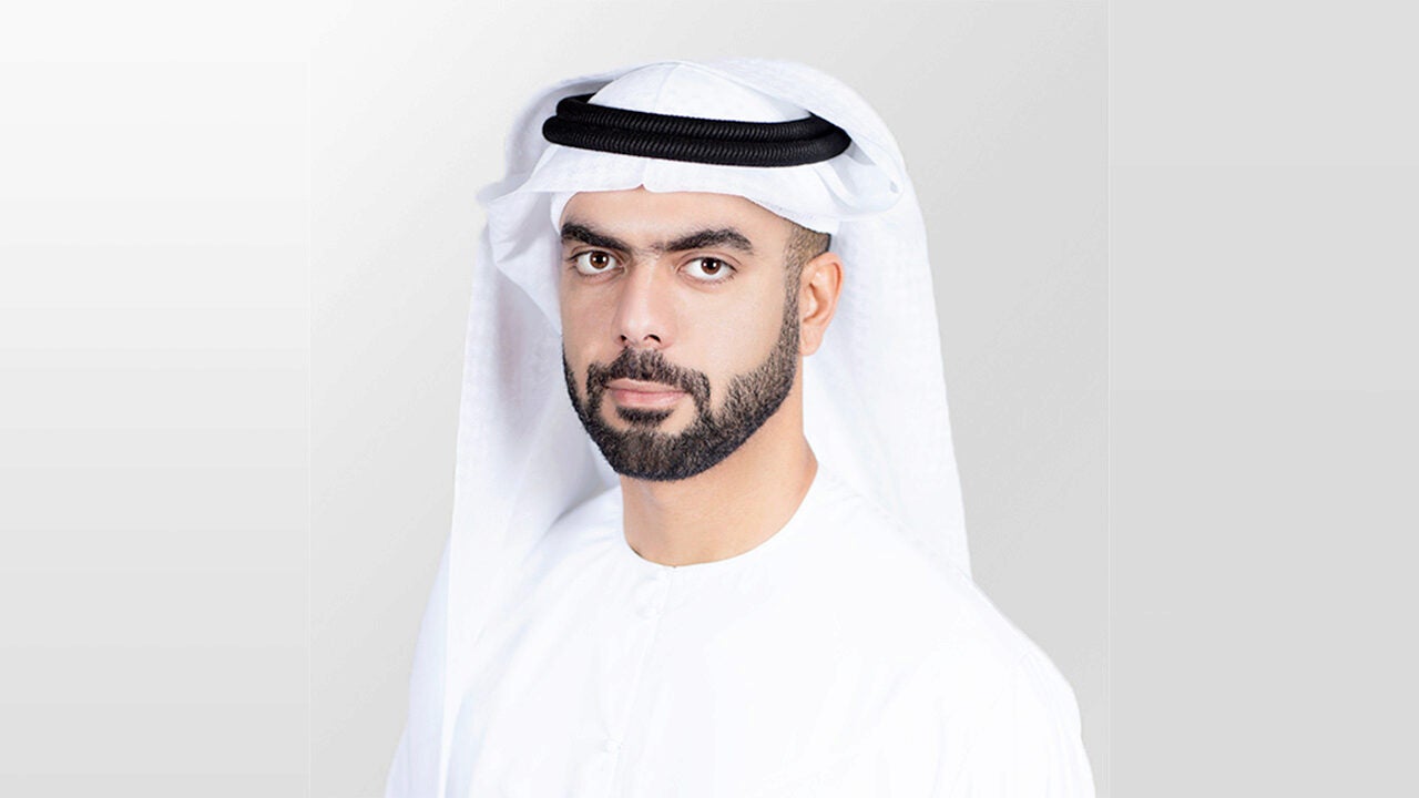 A headshot of a person wearing traditional Middle Eastern attire, including a white keffiyeh and white clothing, on a light gray background.