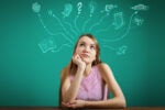 A person sits thoughtfully at a table with various graphics above their head representing ideas like money, love, education, and travel.