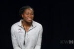 Headshot of a person smiling, wearing a gray "Penn Basketball" top, in front of a dark background.