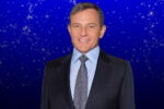 A person in a suit and tie in front of a blue background with sparkling stars.