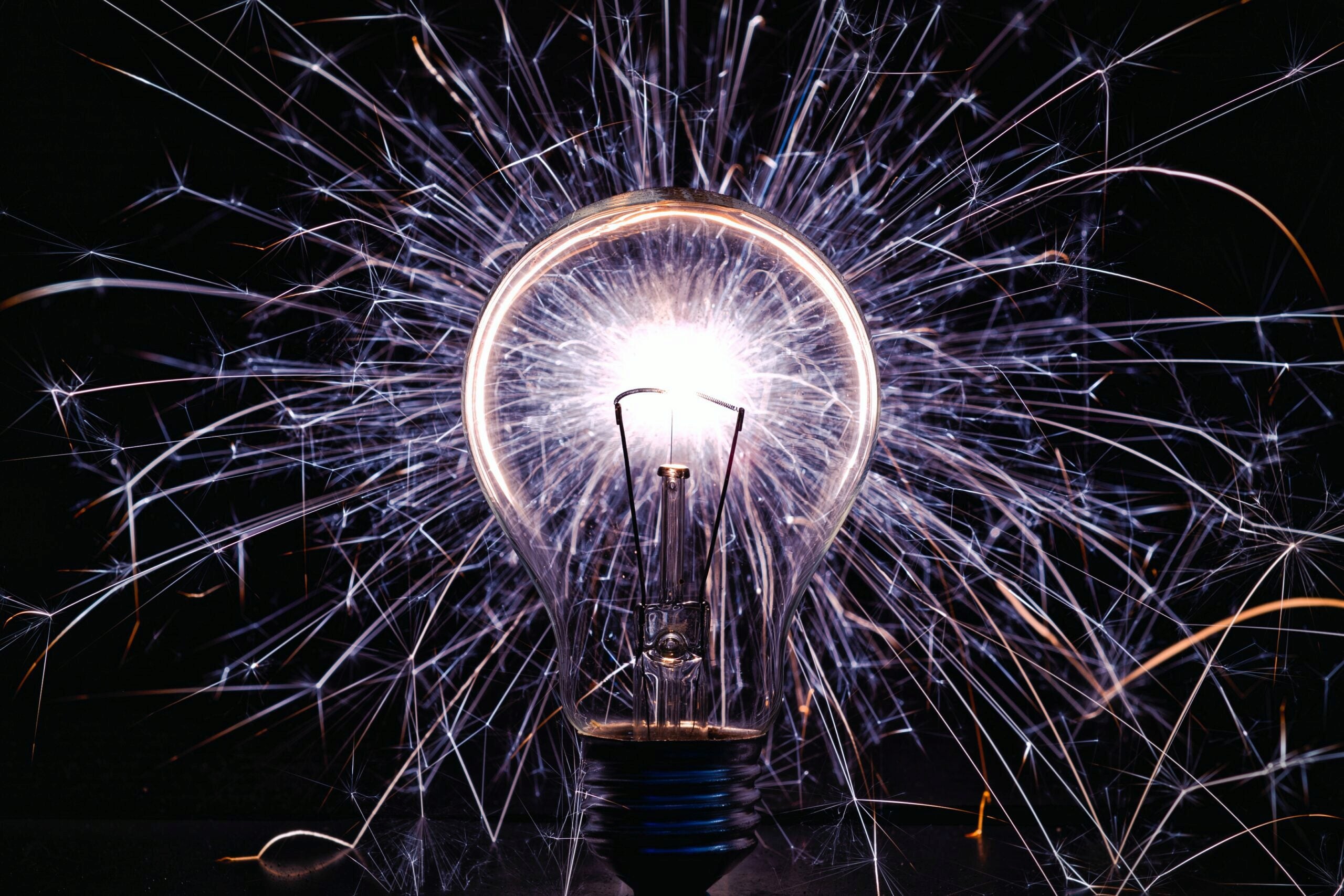 A lit light bulb surrounded by bright, radiating sparks, symbolizing creativity and inspiration.