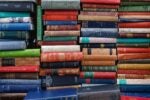 A stack of vintage hardcover books in various colors and sizes, with visible spines showing titles and authors'' names.