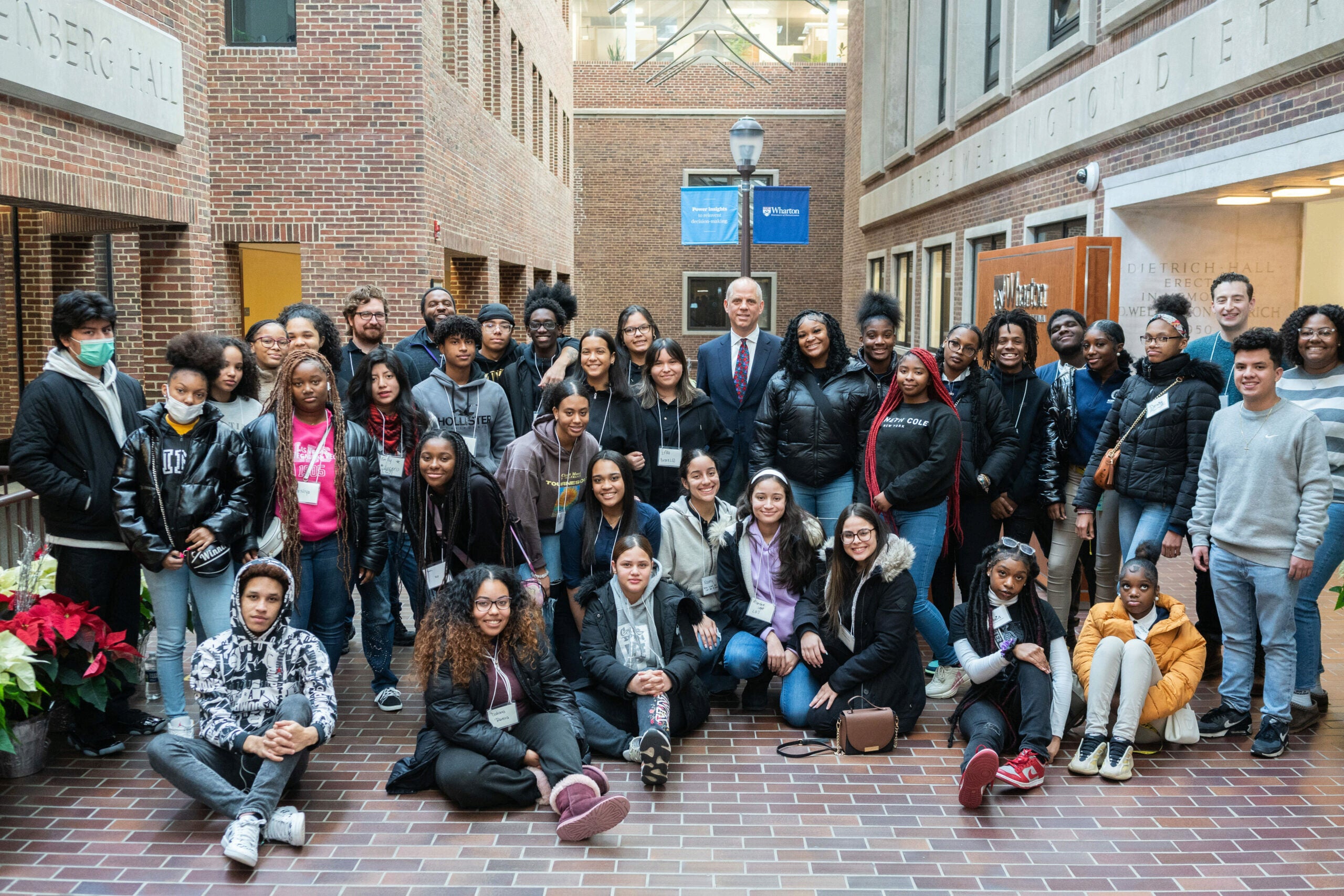 A large group of people gathered in an indoor hallway, smiling for a group photo. They are of diverse backgrounds and appear to be in a university setting.